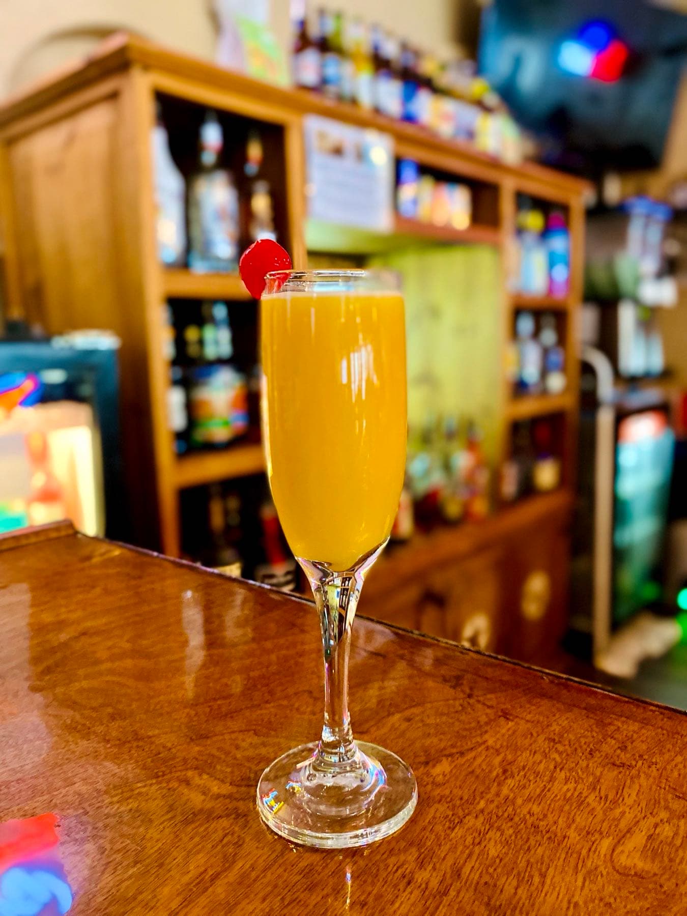 Mimosa-style cocktail with a cherry garnish at the bar