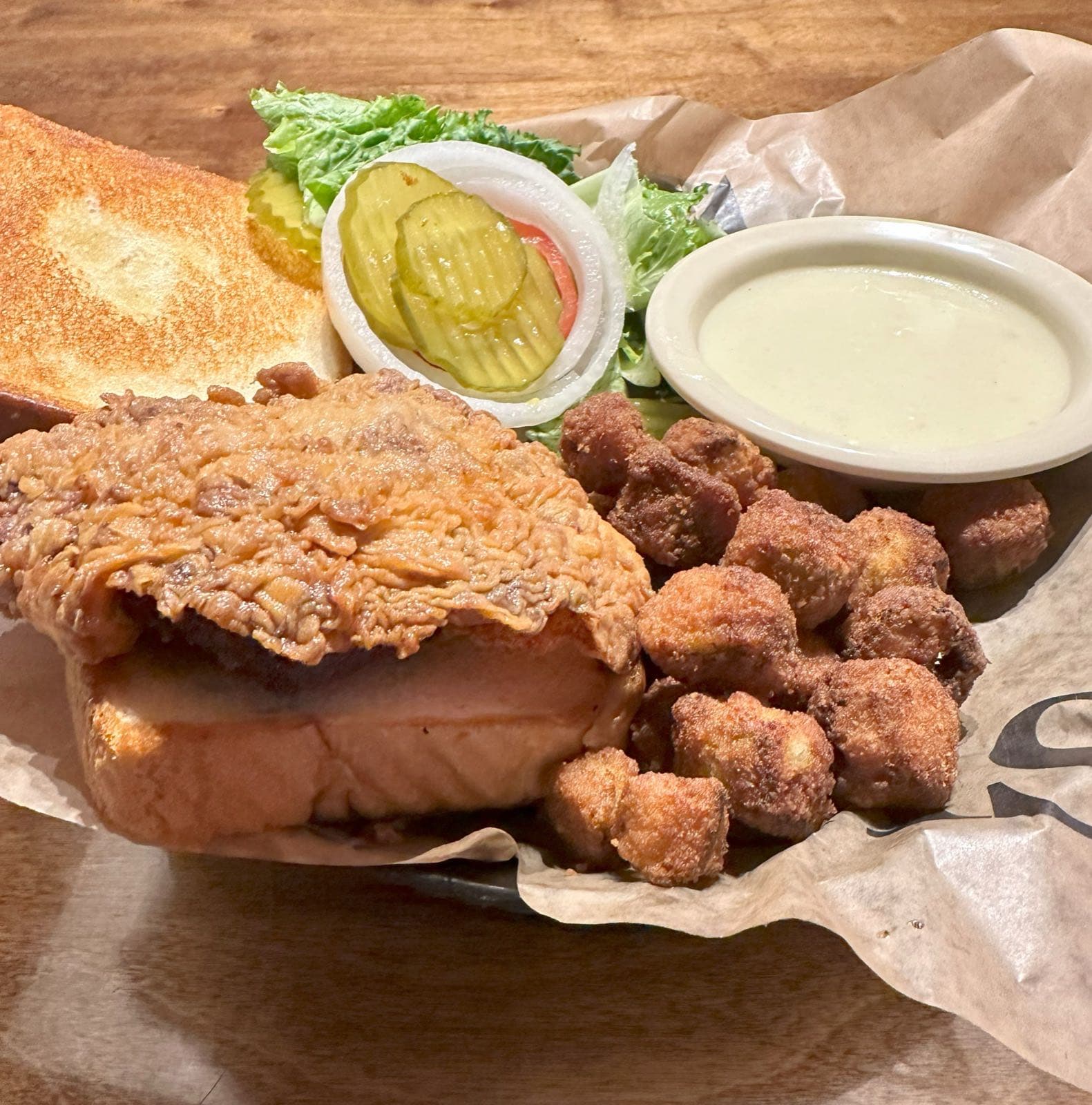 Crispy breaded sandwich with pickles and lettuce, served with fried okra
