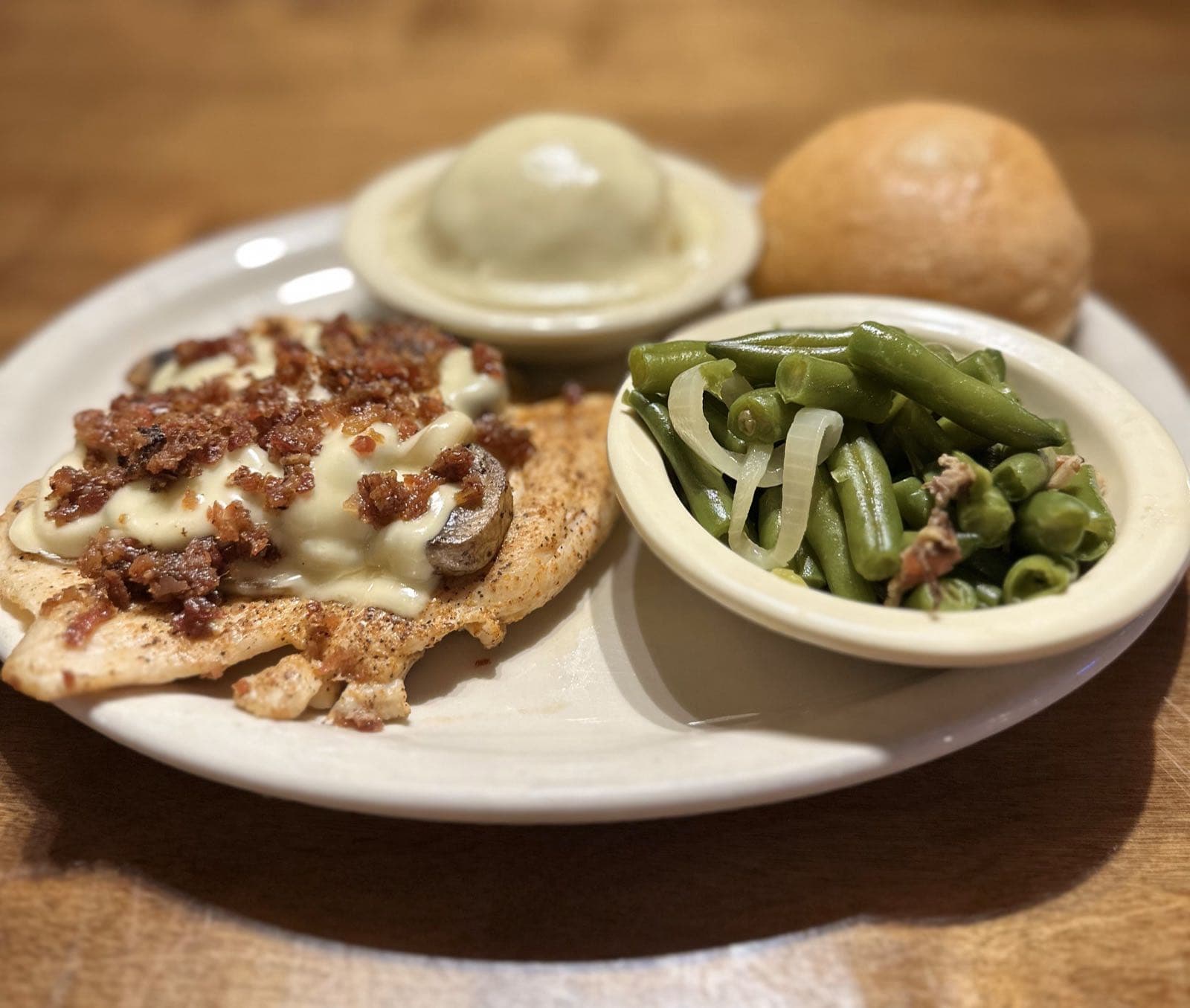 Grilled chicken breast topped with melted cheese, bacon and mushrooms, with mashed potatoes
