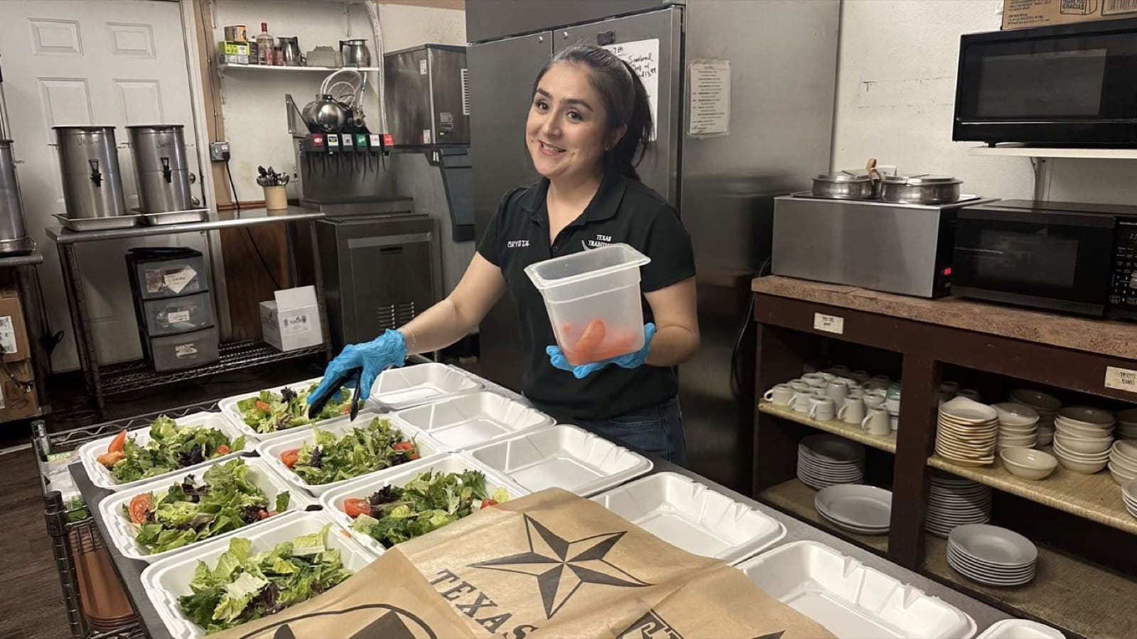 Texas Traditions staff member plating fresh salads into to-go boxes for a group order