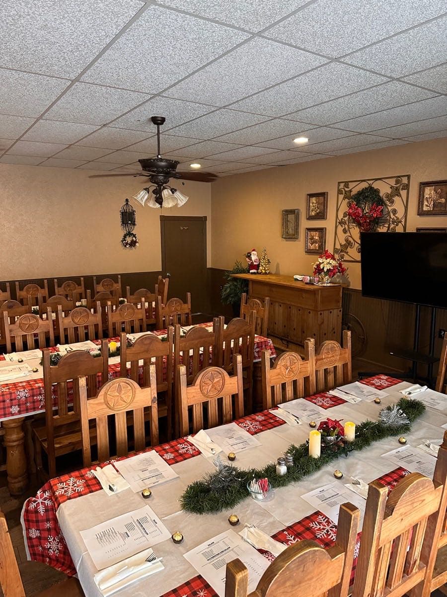 Long table in the party room set with plates, menus, and holiday decor.