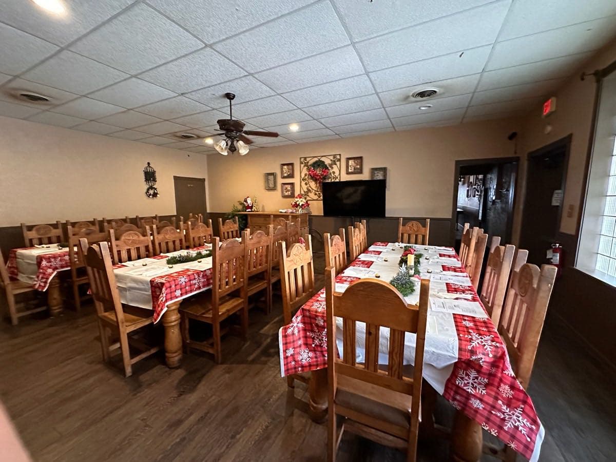 Wide view of the party room set for a holiday gathering, tables arranged for a large group.